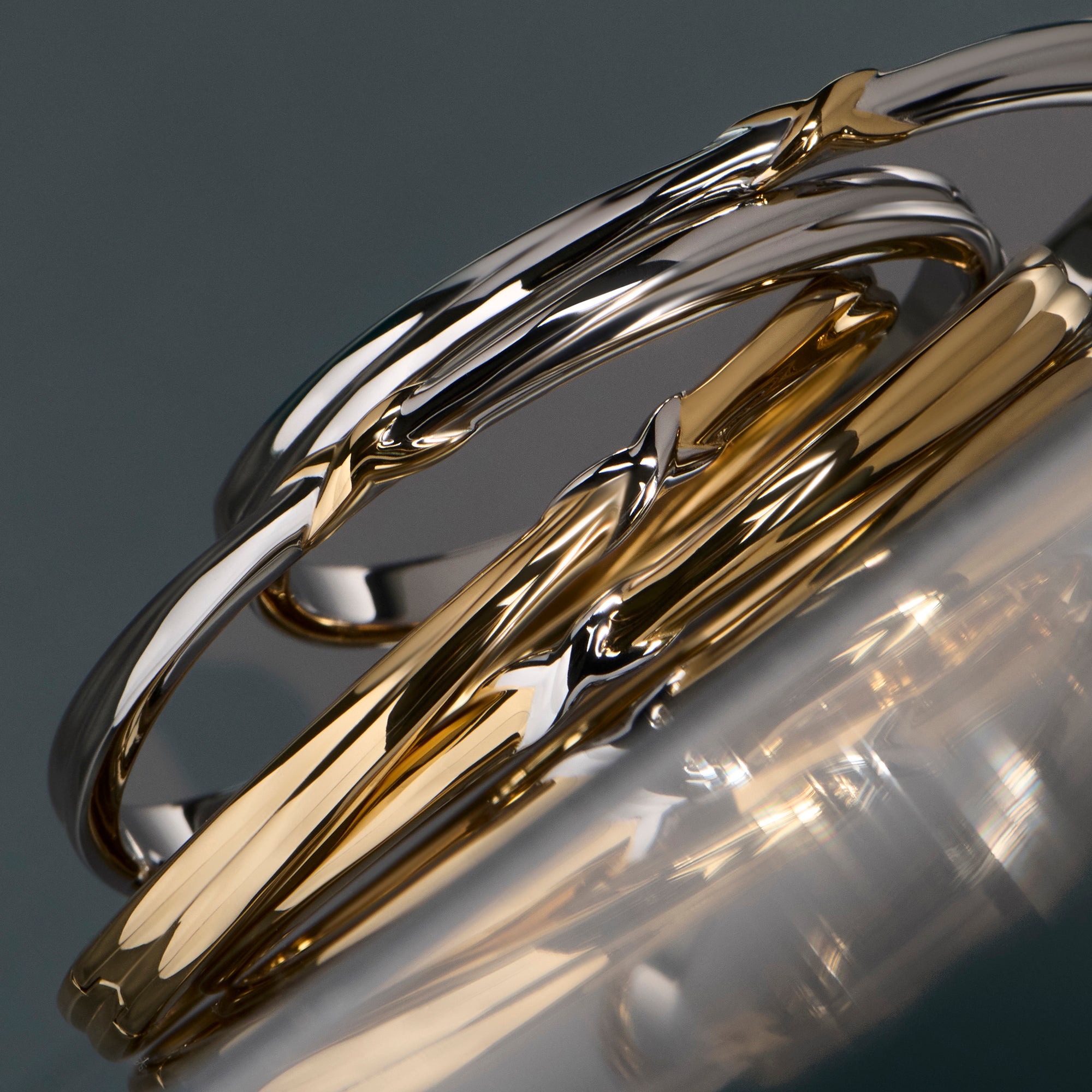 Two-tone stainless steel bangle with sculptural twist design, modern gold and silver minimalist jewelry, hypoallergenic non-tarnish durable rings, elegant everyday stackable jewelry.