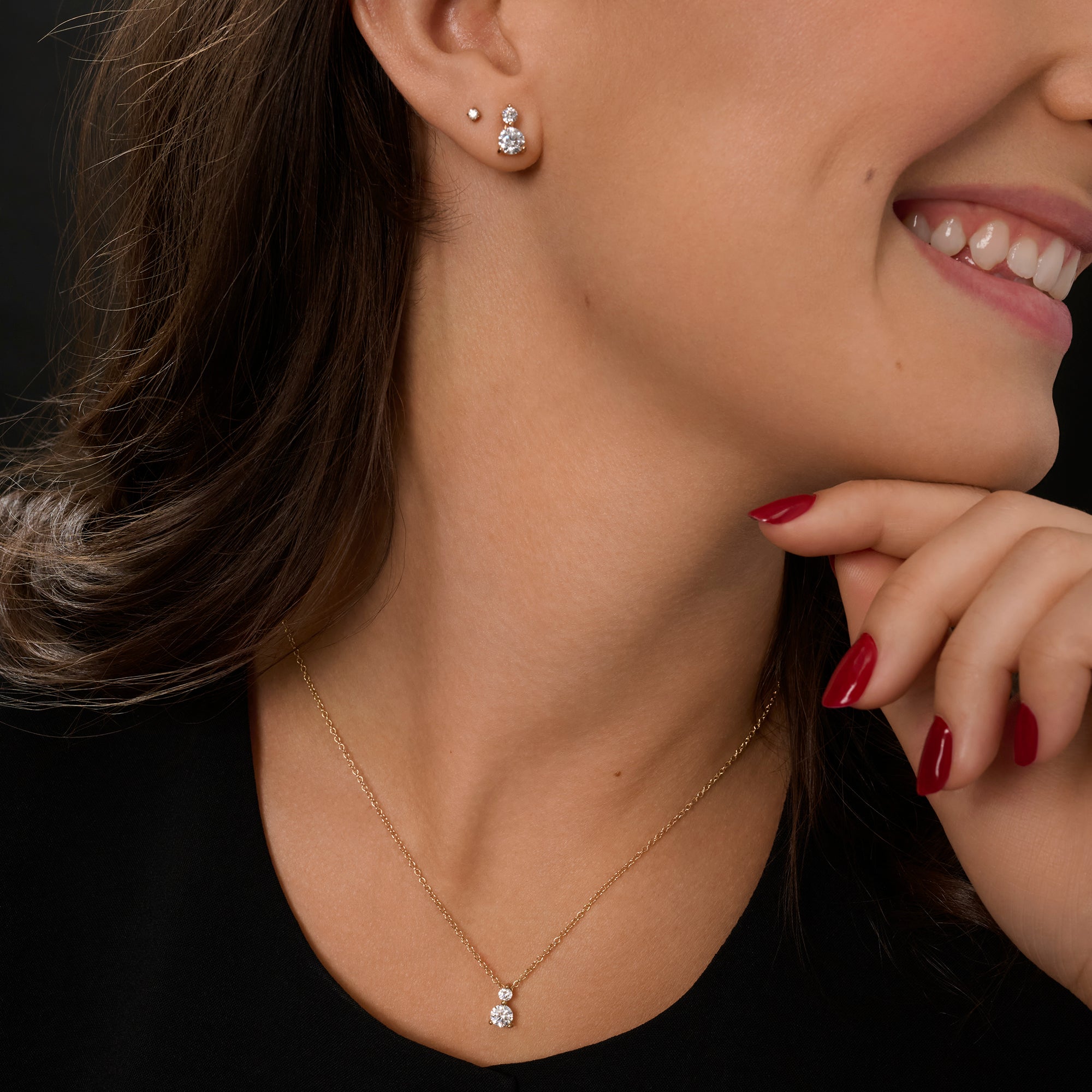 Delicate gold stainless steel necklace with double cubic zirconia pendant styled with matching stud earrings, classic minimalist jewelry with brilliant stones.