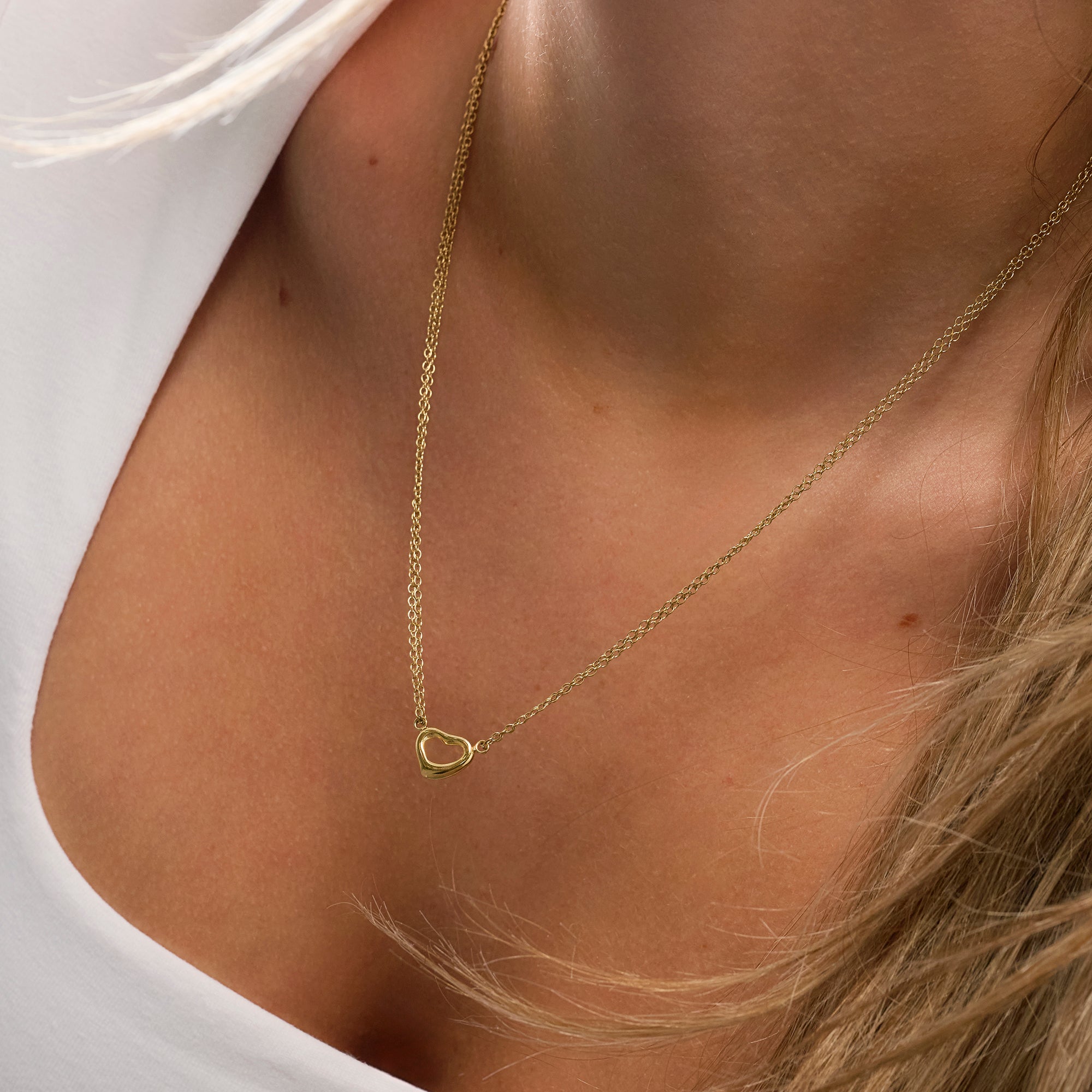 Delicate gold stainless steel heart pendant necklace worn on neckline, minimalist romantic jewelry, hypoallergenic non-tarnish durable everyday necklace, elegant dainty heart jewelry.
